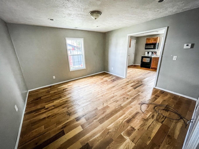 spare room with light wood-type flooring and a textured ceiling