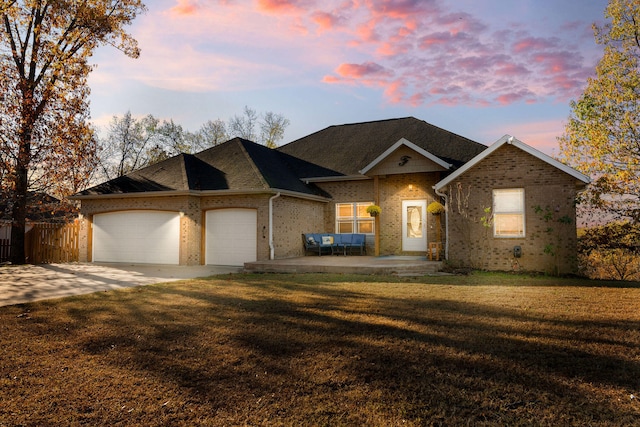 ranch-style house with a lawn, a patio area, and a garage