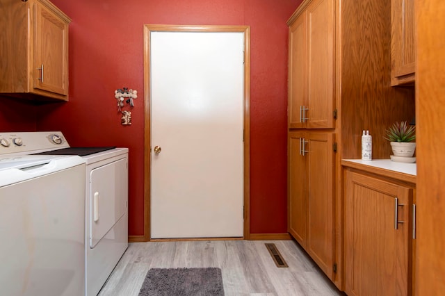 washroom with light hardwood / wood-style flooring, cabinets, and independent washer and dryer