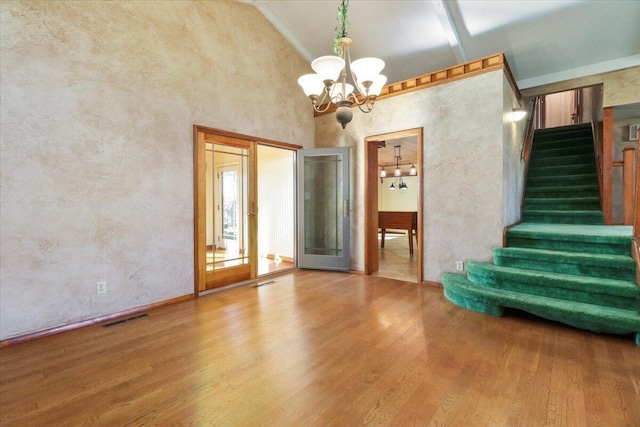 2112 Cambridge Dr, West Plains, MO 65775 - spare room featuring a chandelier, stairs, wood finished floors, high vaulted ceiling, and baseboards