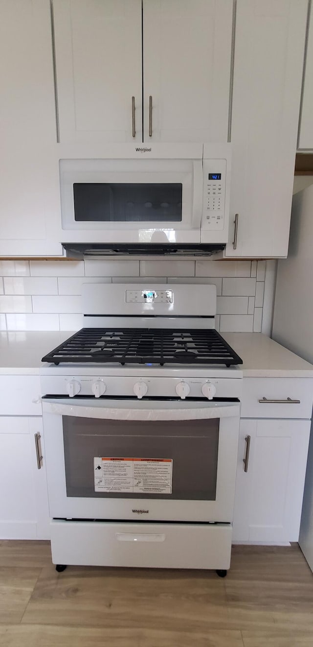 kitchen featuring white cabinets, gas range, tasteful backsplash, and light hardwood / wood-style flooring