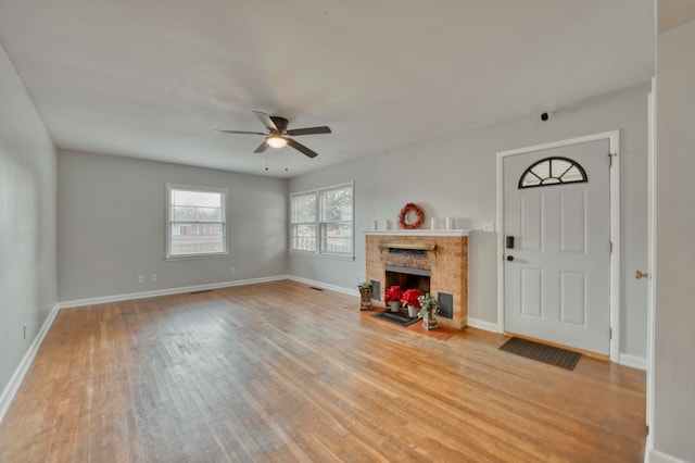 foyer entrance with ceiling fan, light hardwood / wood-style floors, and a brick fireplace