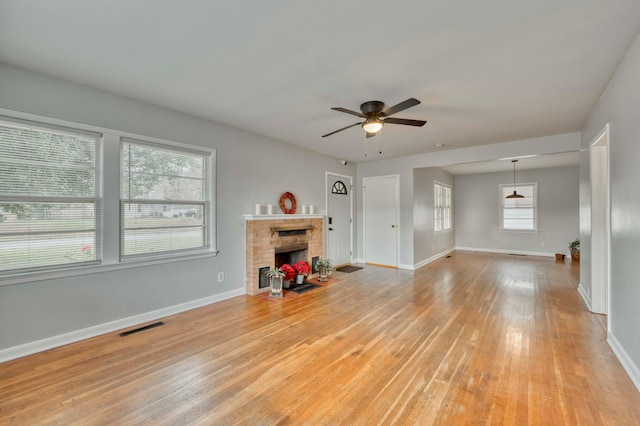 unfurnished living room featuring ceiling fan, light hardwood / wood-style flooring, and a brick fireplace