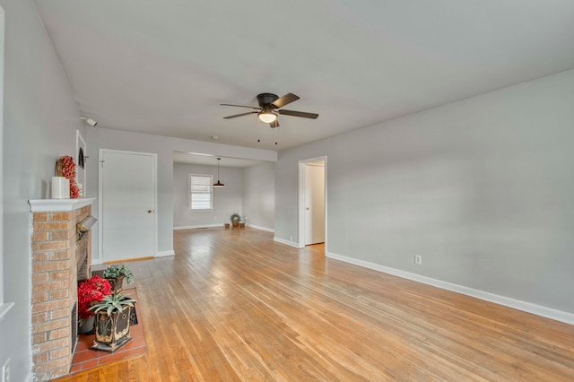 unfurnished living room featuring ceiling fan, light hardwood / wood-style flooring, and a brick fireplace