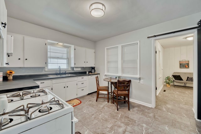 kitchen with a barn door, white appliances, sink, and white cabinetry