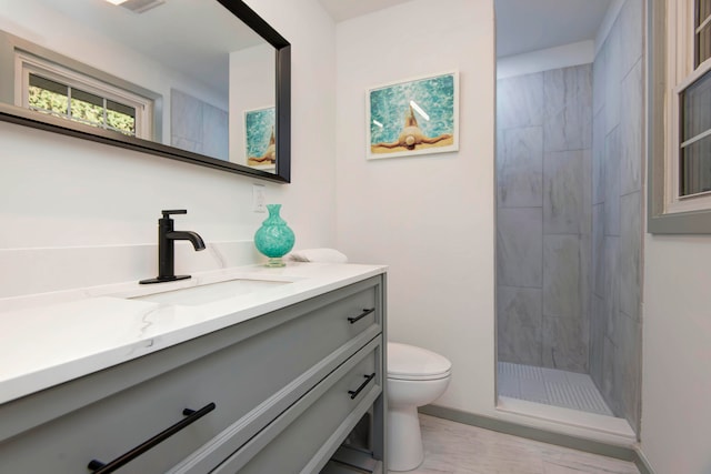 bathroom with tiled shower, vanity, and toilet