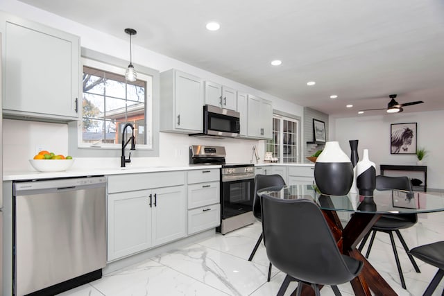 kitchen with appliances with stainless steel finishes, ceiling fan, sink, pendant lighting, and white cabinetry