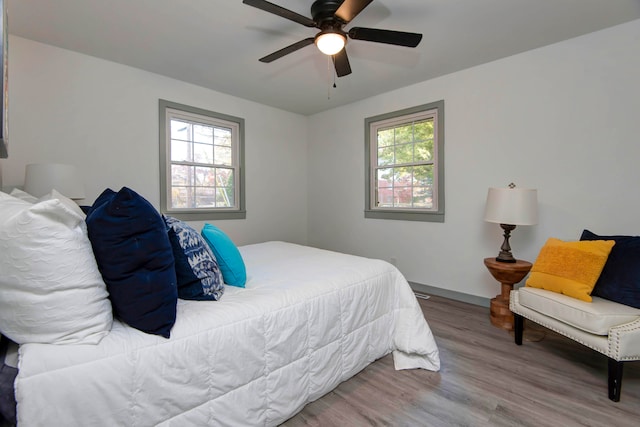 bedroom featuring ceiling fan, wood-type flooring, and multiple windows