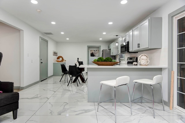 kitchen featuring kitchen peninsula, appliances with stainless steel finishes, and a breakfast bar