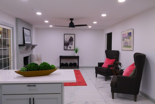 living area featuring ceiling fan and a fireplace