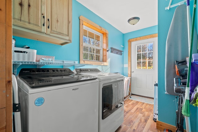 clothes washing area with light hardwood / wood-style floors, cabinets, and independent washer and dryer