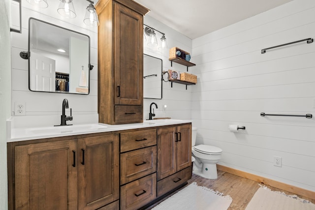 bathroom with vanity, wood walls, toilet, and wood-type flooring