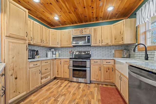 kitchen with backsplash, light brown cabinets, light hardwood / wood-style floors, and appliances with stainless steel finishes