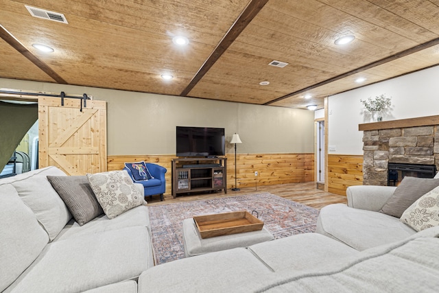 living room featuring a barn door, wood walls, and wooden ceiling