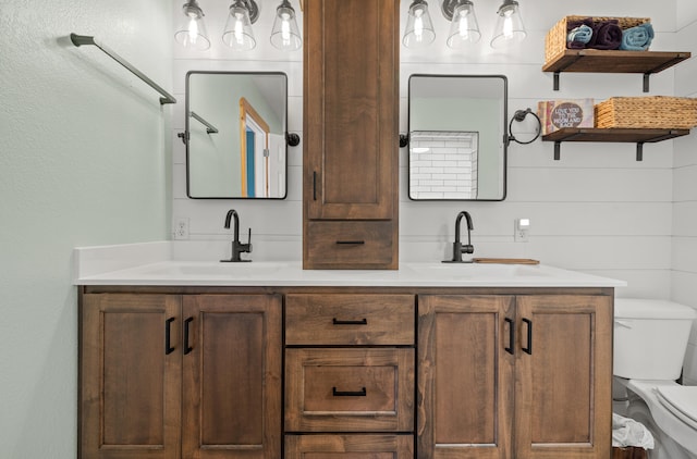 bathroom with vanity, toilet, and wood walls