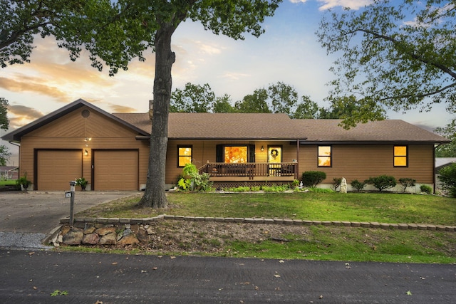 ranch-style home featuring a lawn, a porch, and a garage