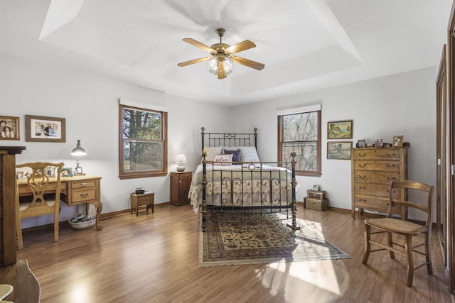 bedroom featuring hardwood / wood-style flooring, a raised ceiling, and ceiling fan