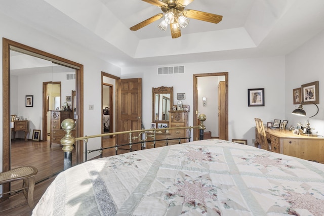 bedroom featuring a closet, a tray ceiling, hardwood / wood-style flooring, and ceiling fan