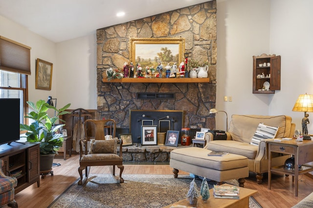 living room with hardwood / wood-style floors and a stone fireplace