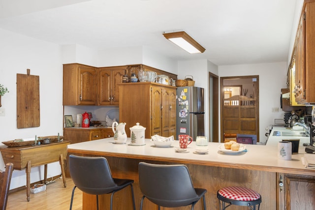 kitchen with a kitchen breakfast bar, kitchen peninsula, stainless steel appliances, and light hardwood / wood-style floors