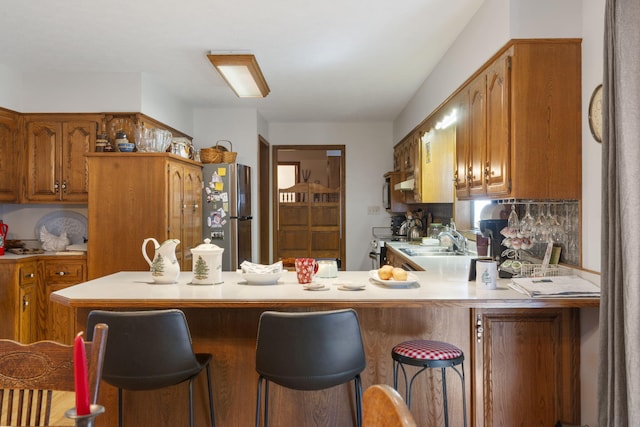 kitchen featuring a breakfast bar area, kitchen peninsula, sink, and stainless steel appliances