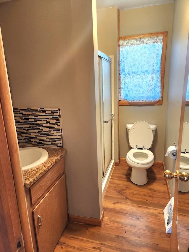 bathroom featuring hardwood / wood-style floors, vanity, toilet, tasteful backsplash, and an enclosed shower