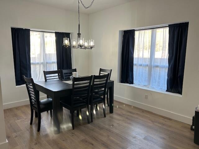 dining room with wood-type flooring and an inviting chandelier