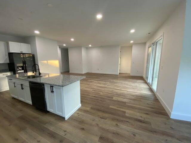 kitchen featuring a kitchen island with sink, hardwood / wood-style floors, white cabinets, and black appliances