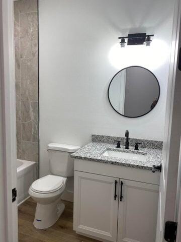 full bathroom with vanity, wood-type flooring, shower / bathtub combination, and toilet