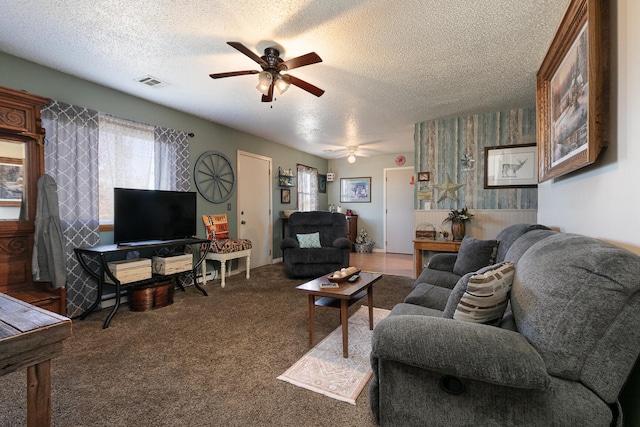 carpeted living room featuring ceiling fan and a textured ceiling