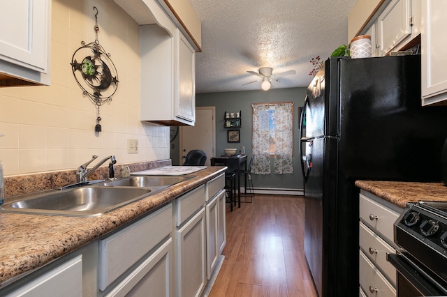 kitchen with sink, baseboard heating, dark hardwood / wood-style floors, a textured ceiling, and black appliances