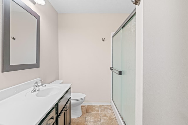 bathroom with tile patterned floors, a shower with door, vanity, and toilet