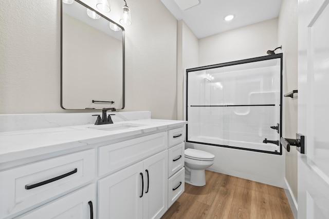 full bathroom featuring combined bath / shower with glass door, wood-type flooring, vanity, and toilet