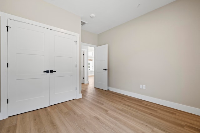 unfurnished bedroom with a closet and light hardwood / wood-style floors