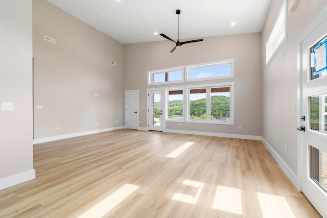 unfurnished living room featuring light wood-type flooring, high vaulted ceiling, and ceiling fan