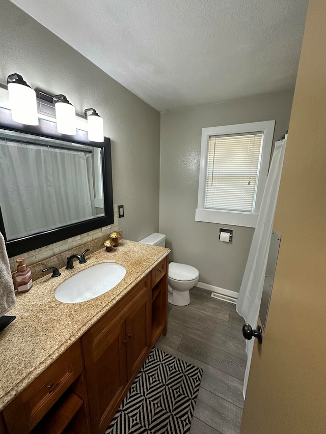 bathroom featuring vanity, wood-type flooring, a textured ceiling, and toilet