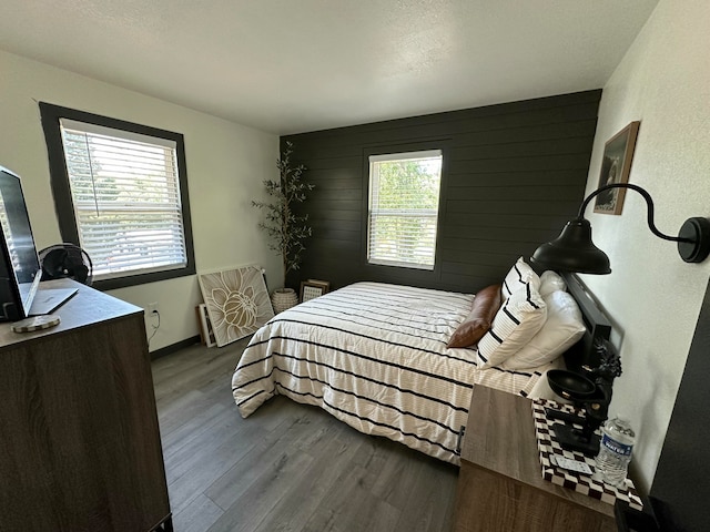 bedroom featuring hardwood / wood-style flooring, wooden walls, and multiple windows