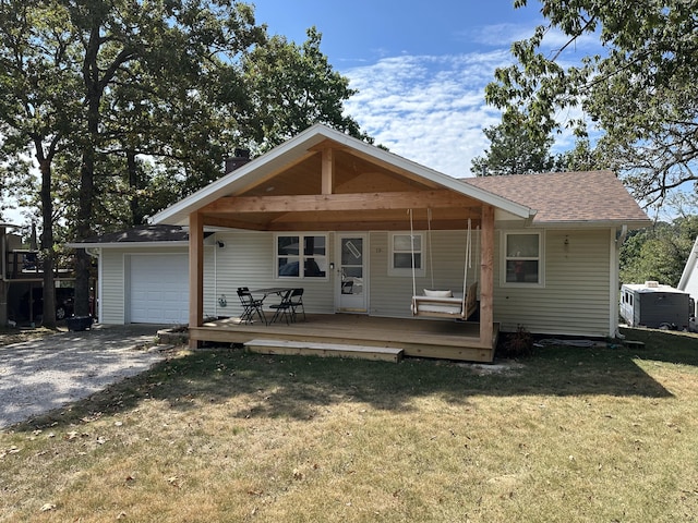 rear view of property featuring central AC, a yard, and a garage