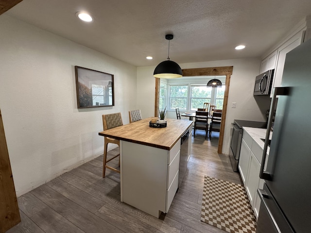 kitchen featuring white cabinets, stainless steel appliances, a kitchen island, and hardwood / wood-style flooring