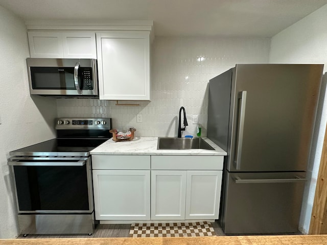 kitchen featuring tasteful backsplash, sink, white cabinets, and stainless steel appliances