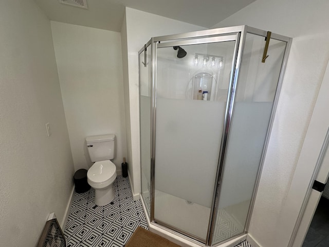 bathroom featuring tile patterned flooring, an enclosed shower, and toilet