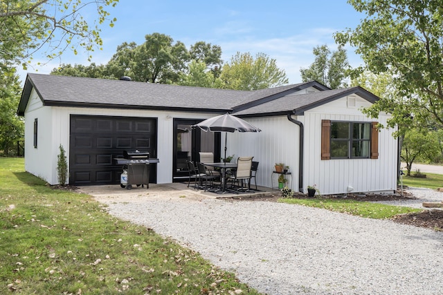 view of front of property with a garage, a patio area, and a front lawn