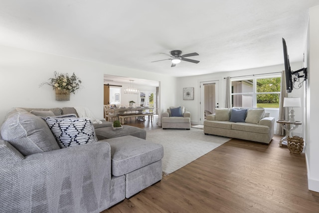 living room with ceiling fan with notable chandelier and dark hardwood / wood-style floors