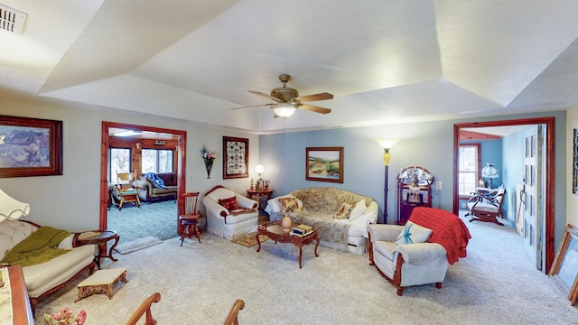 living room featuring carpet, ceiling fan, and a raised ceiling