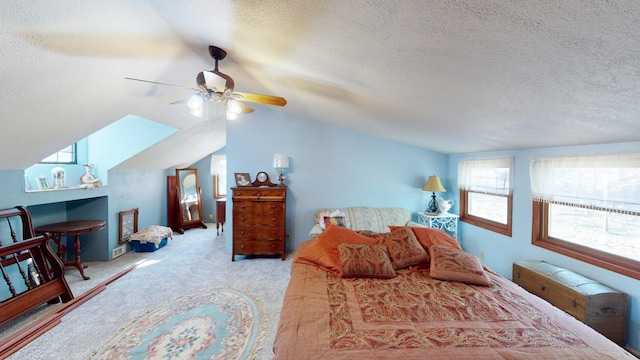 bedroom with ceiling fan, lofted ceiling with skylight, a textured ceiling, and light carpet