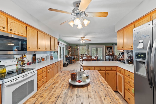 kitchen with ceiling fan, kitchen peninsula, stainless steel appliances, and light hardwood / wood-style flooring