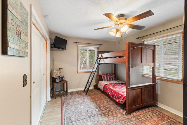 bedroom with ceiling fan, a closet, and light hardwood / wood-style floors