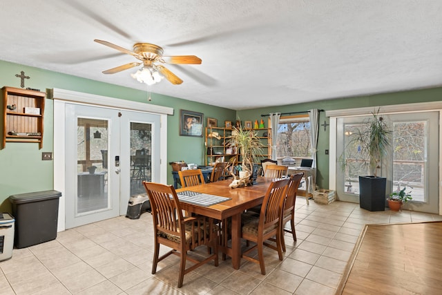 dining area with ceiling fan, light wood-type flooring, a textured ceiling, and french doors