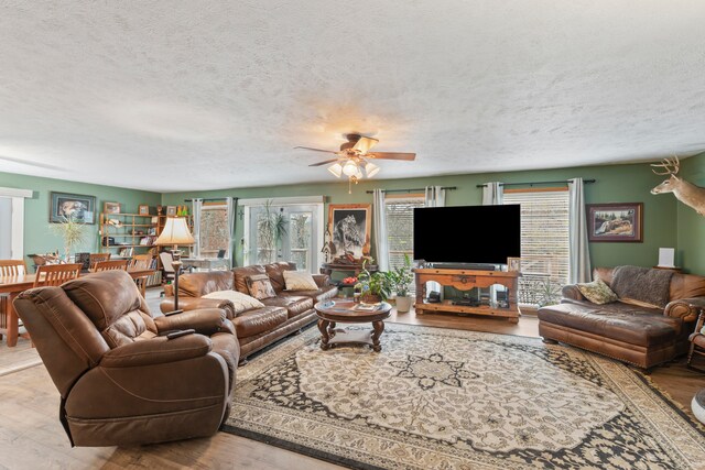 living room with ceiling fan, light hardwood / wood-style floors, and a textured ceiling