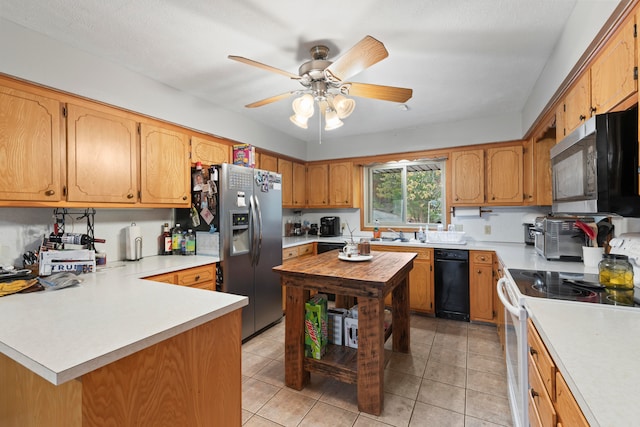 kitchen with appliances with stainless steel finishes, light tile patterned floors, ceiling fan, and sink